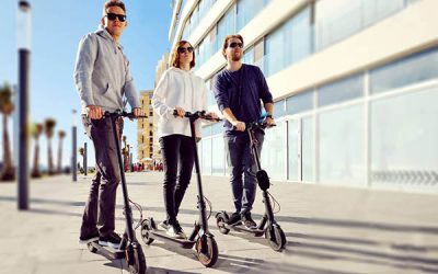 Three best friends young 20s -30s girl and guys spend time outdoors gathered together driving on electric scooter modern land vehicle, easy comfort usage, technology urban transportation concept image